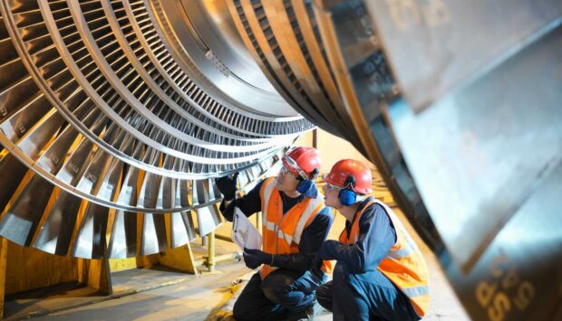 Two engineers inspect turbine in power station