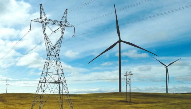 Wind turbines positioned on a plain next to electric grid towers